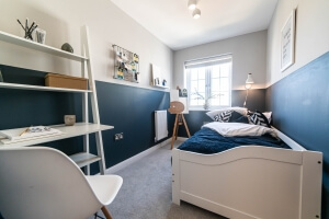 A bedroom with blue walls, single bed and other furniture