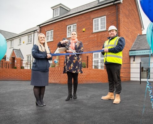 Cavanna employees outside show homes cutting a ribbon to officially open them