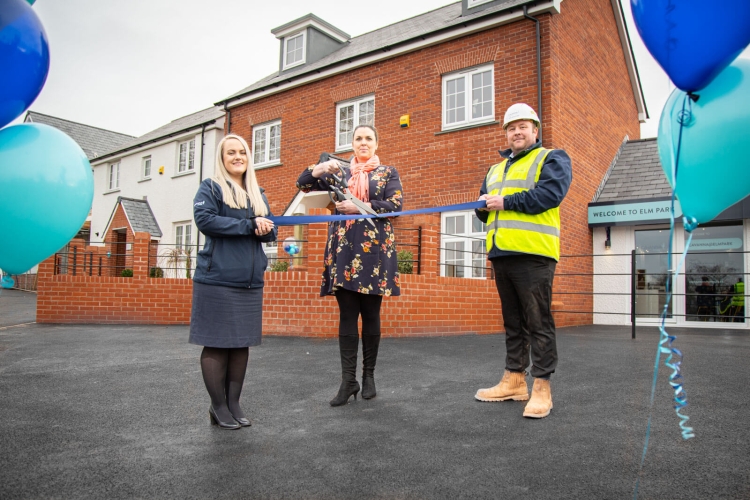 Cavanna employees outside show homes cutting a ribbon to officially open them