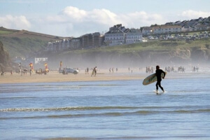 Surfer walking in the waves on a beach in Devon