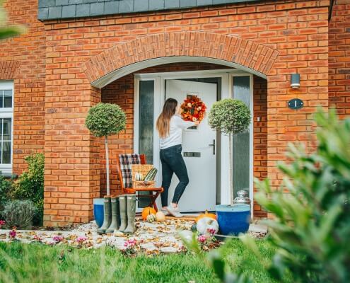 Woman placing an autumnal wreath on the door of a Cavanna home