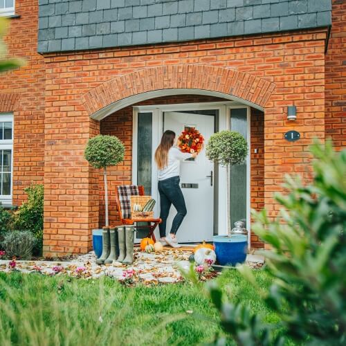Woman placing an autumnal wreath on the door of a Cavanna home